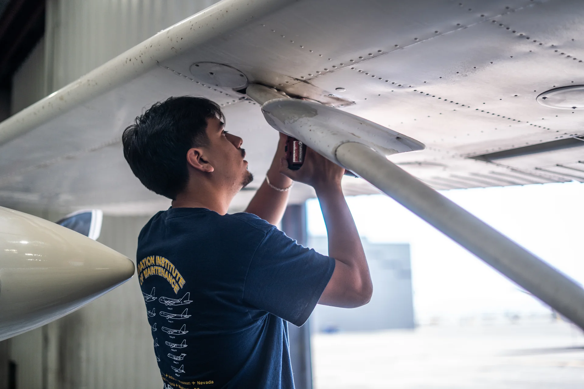 Vegas Aviation aircraft mechanic inspecting the underside of a wing in the hangar